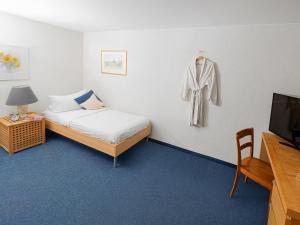ein Schlafzimmer mit einem Bett und einem an der Wand hängenden Bademantel in der Unterkunft Hotel Rhyhof in Frauenfeld