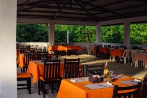 een restaurant met tafels en stoelen met oranje tafellaken bij Majahual Resort in El Majahual