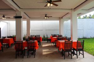 eine Terrasse mit roten Tischen und Stühlen sowie einem Deckenventilator in der Unterkunft Majahual Resort in El Majahual