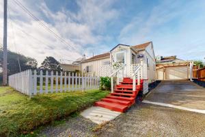 uma casa com uma cerca branca e uma escada vermelha em DnA Tiny beach House em Reedsport