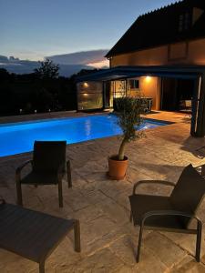 a swimming pool with two chairs and a table at Gîte la bergerie, piscine chauffée, in Couzon