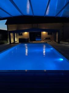 a swimming pool with blue lights in a house at Gîte la bergerie, piscine chauffée, in Couzon