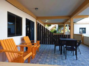 d'une terrasse avec des chaises en bois et une table et des chaises noires. dans l'établissement Beach Side Condos Caye Caulker by CCVH, à Caye Caulker