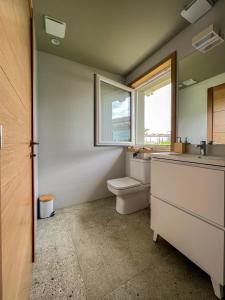 a bathroom with a toilet and a sink and a window at La Quintana De José in Muros de Nalón