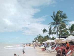 people on a beach with palm trees and the ocean at Casa para temporada 50m da praia in Porto Seguro