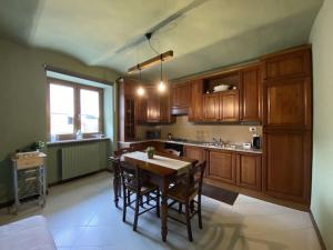 una cocina con armarios de madera, mesa y sillas en La casa dei Nonni Guest House, en Cuneo