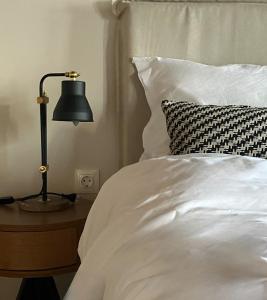 een bed met witte lakens en een lamp op een nachtkastje bij Melofegaro Guesthouse in Palaios Panteleimon