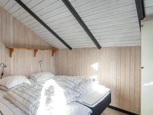 a large bed in a room with wooden walls at 5 person holiday home in Dannemare in Dannemare