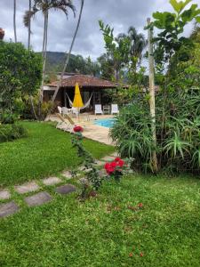 un patio trasero con piscina y una casa en Chalé Casa de Esther en Teresópolis