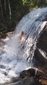 Ein Mann liegt vor einem Wasserfall. in der Unterkunft Sitio Anju in Atibaia