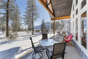a porch with a table and chairs in the snow at Antoine Cabin in Chelan
