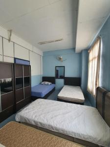 twee bedden in een kamer met blauwe muren bij Deummah Guest Room in Cukai