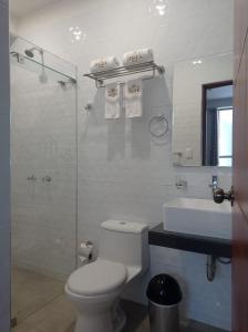 a white bathroom with a toilet and a sink at Hotel Cesar´s in Lima