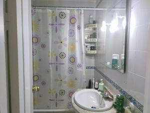 uma casa de banho com um lavatório e uma cortina de chuveiro com flores em SOLEA 17 em Rota
