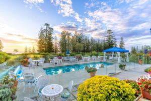 彭特派因的住宿－Sunset Villa Norfolk Island - a Mediterranean inspired villa，一个带白色桌椅和蓝色遮阳伞的游泳池