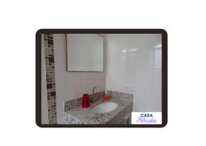 a bathroom with a sink and a mirror at Casa Peruibe. in Peruíbe +18 photos