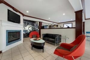 a living room with a fireplace and red chairs at Best Western Edinburgh/Columbus in Edinburgh