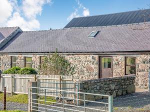 una casa de piedra con techo negro y valla en Bwythyn-y-Saer en Abersoch