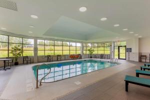 a swimming pool with tables and chairs in a building at Best Western Premier Northwood Hotel in Timmins