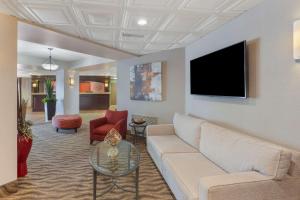 sala de estar con sofá y TV de pantalla plana en Best Western Plus Rose City Suites, en Welland