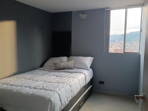 a small bedroom with a bed with a window at Apartamento con vistas a la ciudad (Penthouse) cerca al Estadio, al Boulevard de la 70 y la Avenida 80 (Casinos, restaurantes, malls y otros). in Medellín