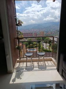 a balcony with two stools and a view of a city at Apartamento con vistas a la ciudad (Penthouse) cerca al Estadio, al Boulevard de la 70 y la Avenida 80 (Casinos, restaurantes, malls y otros). in Medellín
