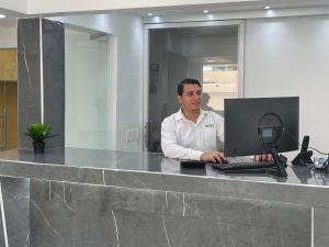 un hombre sentado en un escritorio con un ordenador portátil en Hotel Conquistador Santo Domingo en Santo Domingo