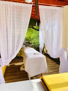 een kamer met een tafel en witte gordijnen bij Villa Paradise in Brazil - Praia de Guaratiba Prado-BA in Prado