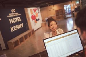 Kenny Stay Jeju Seogwipo في سيوجويبو: امرأة تقف أمام جهاز الكمبيوتر المحمول