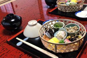 deux plateaux noirs de nourriture sur une table avec des baguettes dans l'établissement 芹生庵, à Kyoto