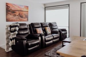 a living room with a black leather reclining couch at Sweetwater Villas in St Helens