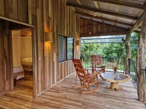 a room with a table and chairs on a deck at Finca Amistad Cacao Lodge in Bijagua