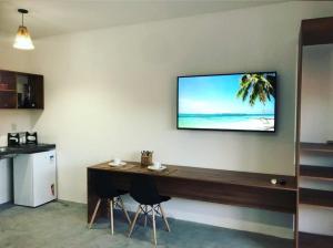 a room with a table and a television on a wall at Marinho Suítes Milagres in São Miguel dos Milagres