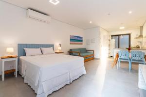a bedroom with a white bed and a table and chairs at Anoa Maresias Studios in Maresias