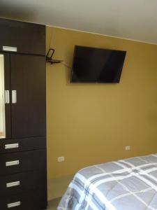 1 dormitorio con 1 cama y TV de pantalla plana en la pared en Matty House, en Lima