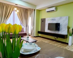 a living room with a tv and yellow walls at Bali Residence Impian Raudah in Melaka