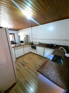 cocina con armarios blancos y suelo de madera en Residencial família Milani 30 metros do mar Torres, en Torres