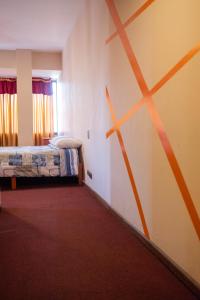 Habitación con cama y pared con líneas naranjas. en Unión Plaza Hotel, en Cochabamba