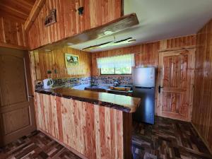 a kitchen with wooden cabinets and a refrigerator at Cabaña Nuevo Amanecer in San José de la Mariquina