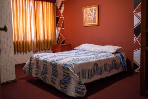 1 dormitorio con 1 cama en una pared roja en Unión Plaza Hotel, en Cochabamba