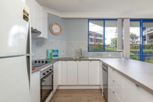a kitchen with white cabinets and a sink at Heritage 103 in Tuncurry