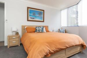 a bedroom with a large bed with an orange blanket at Heritage 103 in Tuncurry