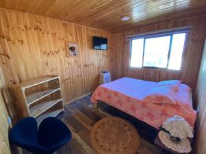 ein Schlafzimmer mit einem Bett in einer Holzhütte in der Unterkunft Cabañas La Chasconita in Constitución