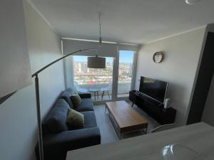 a living room with a couch and a tv at Elegante y acogedor departamento con gran vista, cercano a todo in Concepción