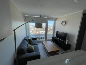 sala de estar con sofá y TV en Elegante y acogedor departamento con gran vista, cercano a todo en Concepción