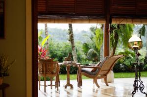 a porch with chairs and a table and a window at Villa Inka Ubud by Nakula in Ubud