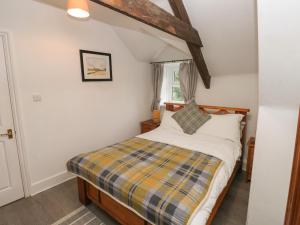 a bedroom with a bed with a checkered blanket at Bwthyn Y Jacdo in Whitechurch