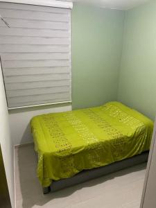 Cama amarilla pequeña en habitación con ventana en Barranquilla Gran Apartamento, en Puerto Colombia