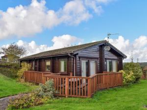 a small wooden house with a large deck at Jasmine Lodge in Woolfardisworthy