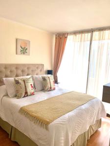 Un dormitorio con una cama blanca con almohadas y una ventana. en CentriK Location Apartments Encomenderos 200, en Santiago